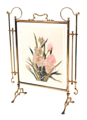 A late Victorian brass and glass panelled fire screen, with scroll framework supports and a painted glass panel of lilies, 76cm high, 46cm wide, 22cm deep.