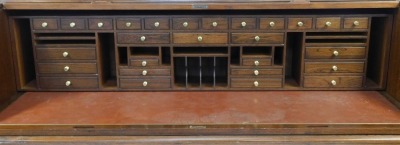 A 20thC oak roll top desk, the tambour front enclosing a dark red leatherette inset with an arrangement of drawers, recesses, etc., the base with a moulded edge above two pedestals each with four drawers, on a plinth base, 127cm high, 183cm wide, 76cm dee - 2