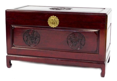 A Chinese cherry wood blanket chest, the rectangular top carved with a roundel depicting a flowering tree, the front carved with two further roundels, with a brass clasp, on shaped legs, 58cm high, 101cm wide, 51cm deep.