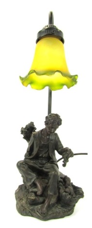 A 20thC table lamp, with frosted yellow and green trumpet glass shade above a figure of a young man seated beside two puppies in basket, 47cm high.