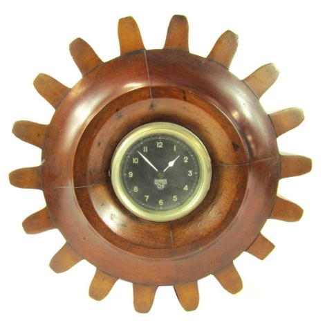 A WW1 propeller shaft Smiths mantel clock, with circular dial bearing black Arabic numerals, quartz movement, the case carved as a cog, 30cm diameter.