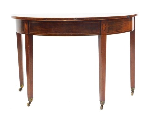 A George III mahogany D end table, the top inlaid with boxwood and ebony banding, the apron with similar banding and inlaid shell motifs, raised on square tapering legs on castors, 72cm high, 114cm wide, 57cm deep.