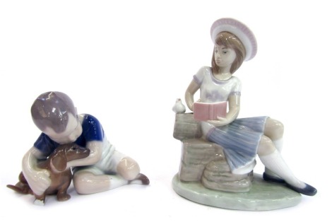 Two Continental figures, comprising a Lladro figure of a girl, seated on hay baskets reading book, 16cm high, and a Bing & Grondahl child with dog, 8cm high. (AF, 2)