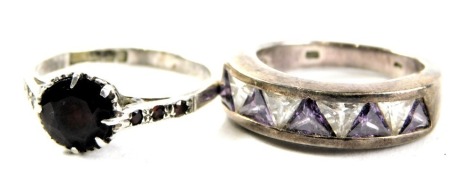 Two silver dress rings, comprising a half hoop silver dress ring with triangular cut amethyst and CZ stones, and a further example set with garnets, boxed. (2)