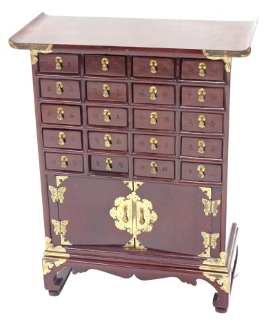 A Chinese small hardwood cabinet, with brass mounts and arrangement of twenty drawers and two doors, each with elaborate butterfly shaped handles, on bracket feet, 76cm high, 59cm wide.