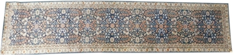 A Persian style runner, with a design of flowers, on a navy blue ground, one wide and various narrow borders, with blue bound edging, 382cm x 87cm.