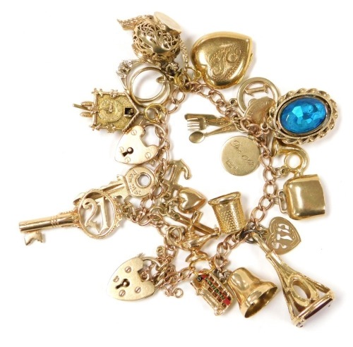 A 9ct gold curb link charm bracelet, with nineteen charms as fitted, on two heart shaped padlock clasps, 51.9g all in.