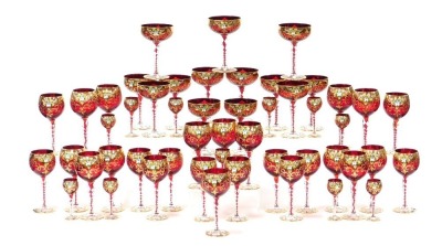 A mid 20thC Venetian ruby glass suite of table glassware, over decorated in enamel with flowers, gilt heightened, comprising thirteen champagne coupes, fourteen red wine and thirteen white wine glasses and eleven liqueur glasses.