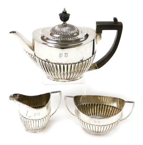 An Edward VII silver three piece tea service, of semi fluted form, monogram engraved, comprising teapot, cream jug and twin handled sugar bowl, Goldsmiths & Silversmiths Company, London 1907, 27.56oz.