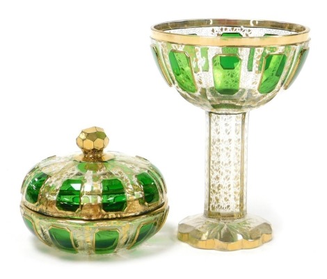 A late 19thC Moser style green and clear glass goblet, the octagonal faceted bowl with green glass reserves, gilt heightened, raised on a faceted stem and foot, 16cm high, together with a similar faceted glass powder bowl and cover, 11cm wide. (2)