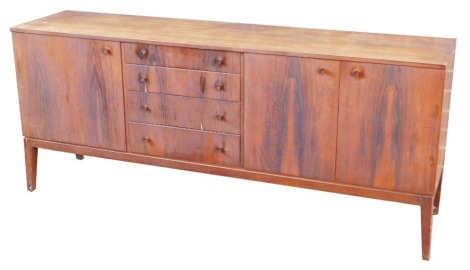 A mid century rosewood sideboard, having four central graduated drawers, flanked by a cupboard door to the left, and a pair of cupboard doors to the right, raised on tapering square legs, 78cm high, 183.5cm wide, 45cm deep.