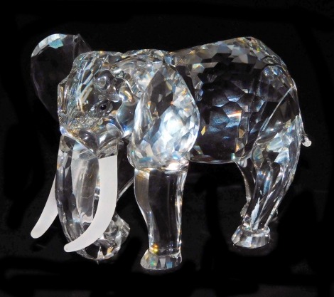 A Swarovski crystal elephant, modelled in standing pose, with frosted glass tusks, 12cm long.