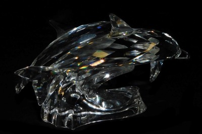 A pair of Swarovski crystal dolphins, modelled riding the crest of a wave, 12.5cm long. - 2