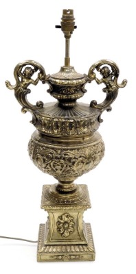 A late 20thC continental brass table lamp, of figural twin handled form, embossed with baroque motifs and foliage, on an integral plinth, 59.5cm high.