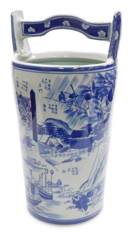 A Chinese blue and white pottery water bucket, decorated with Chinese landscapes and figural scenes, the handle with floral decoration, 50cm high.