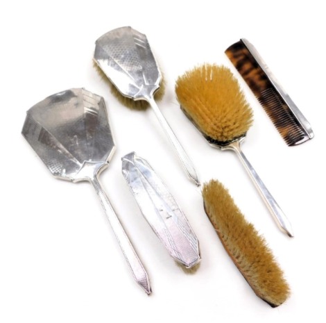 A George V silver dressing table set, with Art Deco engine turned decoration, comprising; hand mirror, comb, pair of hair brushes and a pair of clothes brushes, Birmingham 1934