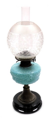 An early 20thC oil lamp, with an opaque shade decorated with flowers, an amber glass central reservoir on a cast iron base, with chimney, 58cm high.