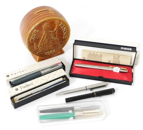 A Parker 61 Flighter Deluxe fountain pen, further fountain and ballpoint pens, and a pottery 1964 one penny money box. (a quantity)