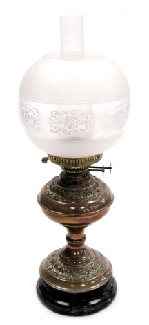 An early 20thC duplex copper oil lamp, with embossed foliate decoration, on a socle base, glass chimney, with frosted and clear glass shade, etched with a band of flowers, 56cm high.