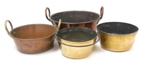 Two graduated twin handled copper jam pans, 43cm and 36cm wide, together with two brass cooking pots, one with cast iron swing handle. (4)