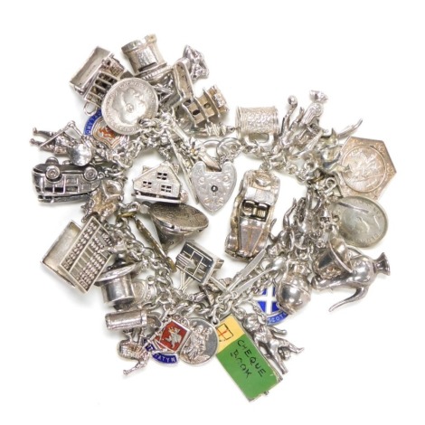 A silver curb link charm bracelet, with forty eight charms, as fitted, on a heart shaped padlock clasp, with safety chain, 3.61oz.