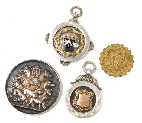 An Abergavenny Dog Show silver medal, obverse with the town's coat of arms and motto, verso various breeds of dogs, silver and enamel school medallion, etched details, further silver gilt medallion, and a 19thC brass gaming token. (4)