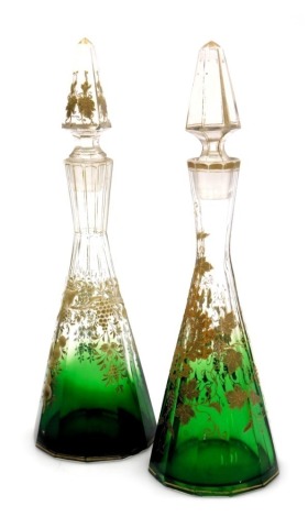 A pair of late 19thC continental glass decanters, of faceted outswept form, gilt decorated with vines and rococo scrolls, 29cm high. (AF)