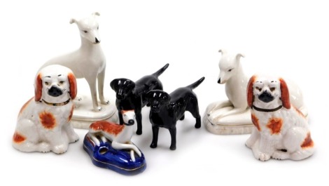 Two Beswick pottery figures of black labradors, a porcelain Staffordshire style inkwell modelled with a recumbent greyhound, two Italian white glazed pottery figures of dogs, and a pair of Staffordshire spaniels. (a quantity)