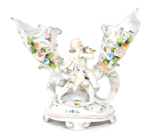 A late 19thC continental porcelain double cornucopia vase, of rococo form, encrusted and painted with flowers, with a cherub seated centrally, raised on an oval rococo base, 22cm wide.