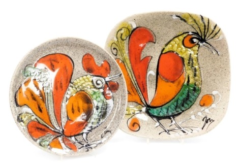 Two late 20thC pottery plates, probably French, decorated with stylized roosters, signed, 24.5cm and 28.5cm wide.