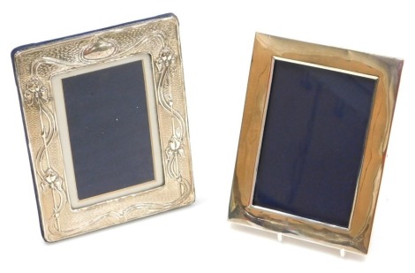 An Elizabeth II Art Nouveau style silver strut photograph frame, embossed with irises, London 2016, 19cm x 14.5cm, and an Edward VII silver photograph frame, of plain form, Chester 1902, 17.5cm x 13cm. (2).