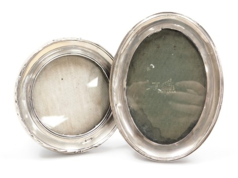 A George V silver strut photograph frame, of plain, oval form, Birmingham 1915, 17cm x 13cm, and another of circular, plain form, Birmingham 1917, 13.5cm wide, (2)