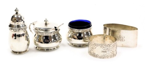 An Elizabeth II silver three piece cruet, comprising pepper pot, open salt with blue glass liner, and mustard pot with blue glass liner, each piece decorated with a band of Celtic influence, with raised roundels, Birmingham 1953, together with a EPNS spoo