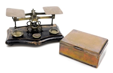 A set of Victorian brass postal scales, on an ebonised base, with weights, 20cm wide. together with a State Express Cigarettes silver plated box, with engine turned sunburst engraving, 12cm wide, 9cm deep. (2)