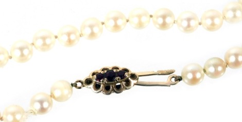 A string of uniform cultured pearls, on a 9ct gold and garnet three stone clasp, 46cm long.