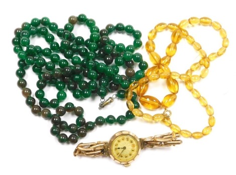 A mid century lady's gold plated wristwatch, circular enamel dial bearing Arabic numerals, on an elasticated strap, together with a string of green agate beads, and a string of faux amber beads. (3)