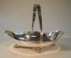 A George V silver swing handled cake basket of oval form on scrolled legs by Walker & Hall