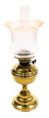 An early 20thC duplex brass oil lamp, with a glass chimney and frosted frilled glass shade, 56cm high.