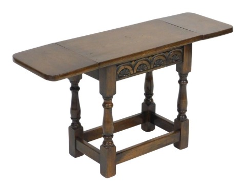 An Old Charm oak drop leaf occasional table, raised on baluster turned supports united by a box stretcher, 53cm wide.