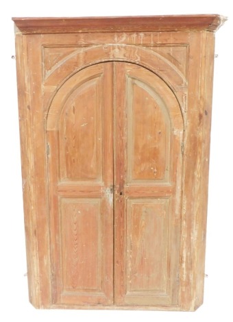 A Georgian pine corner cupboard, the outswept pediment over a pair of arched panelled doors, opening to reveal a turquoise painted sunburst dome over four curved shelves, raised on a plinth base, 164.5cm high, 113cm wide, 54cm deep.