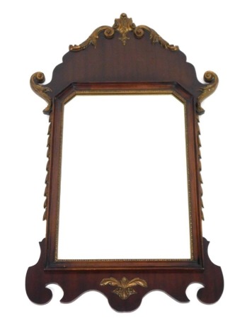 A Georgian style mahogany and gilt wood wall mirror, carved with hairbells and foliate scrolls, inset with a canted rectangular plate, 82cm x 44.5cm.