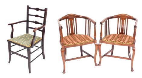 A pair of Edwardian mahogany tub armchairs, upholstered in overstuffed repeating heart shaped pattern fabric, raised on slender cabriole legs united by a H stretcher, 52cm wide, together with a beech ladder back carver chair, with overstuffed seat, raised