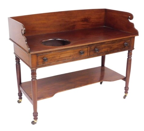 A Victorian mahogany wash stand, with a galleried top, and bowl recess, over two frieze drawers, raised on turned legs united by a shaped under tier, brass capped on castors, 100cm high, 130cm wide, 58cm deep.