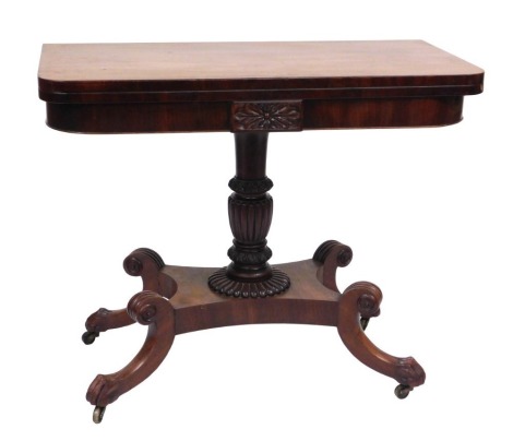 A George IV mahogany fold over tea table, raised on a fluted and foliate carved column, above a quatrefoil base, on four scroll legs, terminating on lion's paw feet, on brass castors, 74m high, 92cm wide, 45.5cm deep.