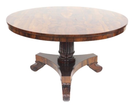 A William IV rosewood tilt top circular dining table, raised on a fluted column, over a tri-form base on channelled scrolled feet, 72cm high, 125cm diameter.