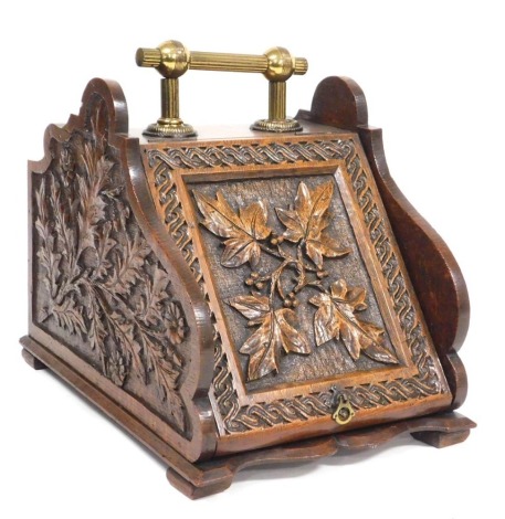 A Victorian oak coal box, with brass carrying handle, carved to the sides and hinged lid, with holly leaves and berries, 29cm wide, 45cm deep.