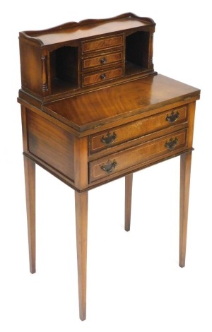 A Georgian reproduction mahogany ladies writing desk, the upper section with three central drawers flanked by recesses and turned pilasters, above a hinged writing slope, over two long drawers, raised on tapering square legs, 99cm high, 53cm wide, 37.5cm 