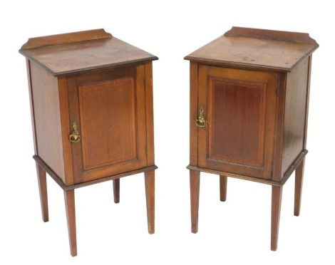 A pair of Edwardian mahogany pot cupboards, with satinwood crossbanding and line inlay, with a single door opening to reveal a shelf, raised on tapering square legs, 80cm wide, 42cm high, 39.5cm deep.