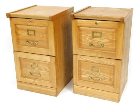 A pair of light oak two drawer filing cabinets, 70cm high, 41cm wide, 45cm deep.