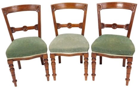 Three Victorian mahogany dining chairs, with overstuffed serpentine seats, raised on turned legs.